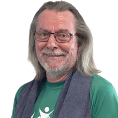 Portr&auml;t eines Mannes mit langen Haaren, Brille und gr&uuml;nem Shirt, der freundlich in die Kamera l&auml;chelt.