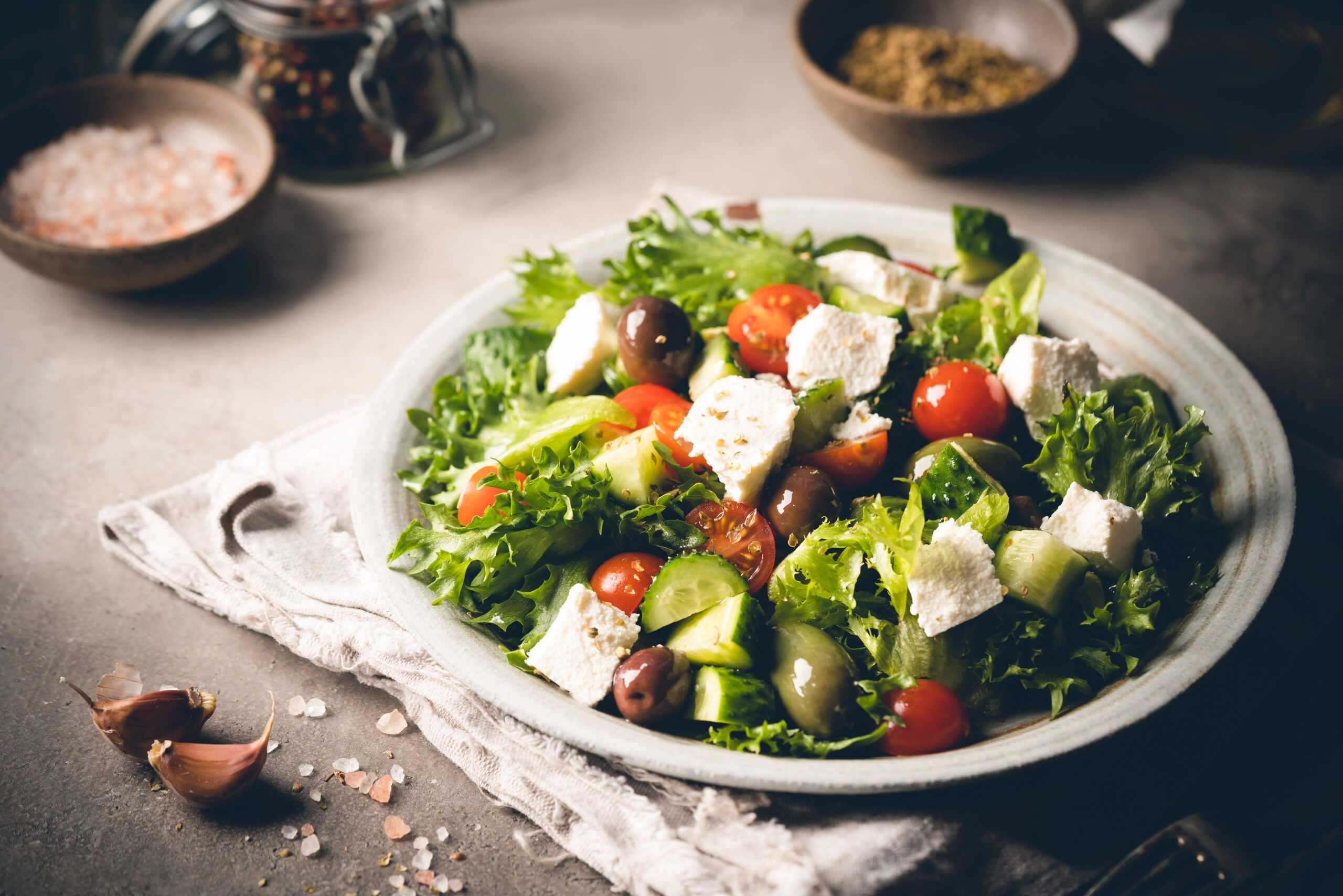 Classic vegetable salad with fresh olives, tomatoes, cucumbers, greek cheese feta and olive oil on gray background.
